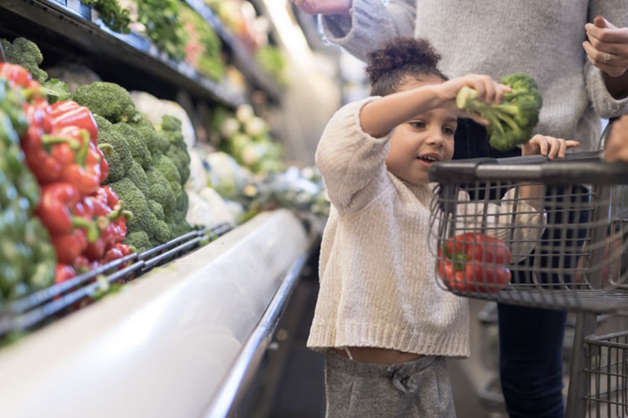 Child picking up vegetables in a food shop